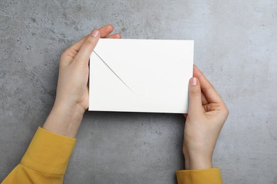 Photo of Woman with envelope at grey table, top view