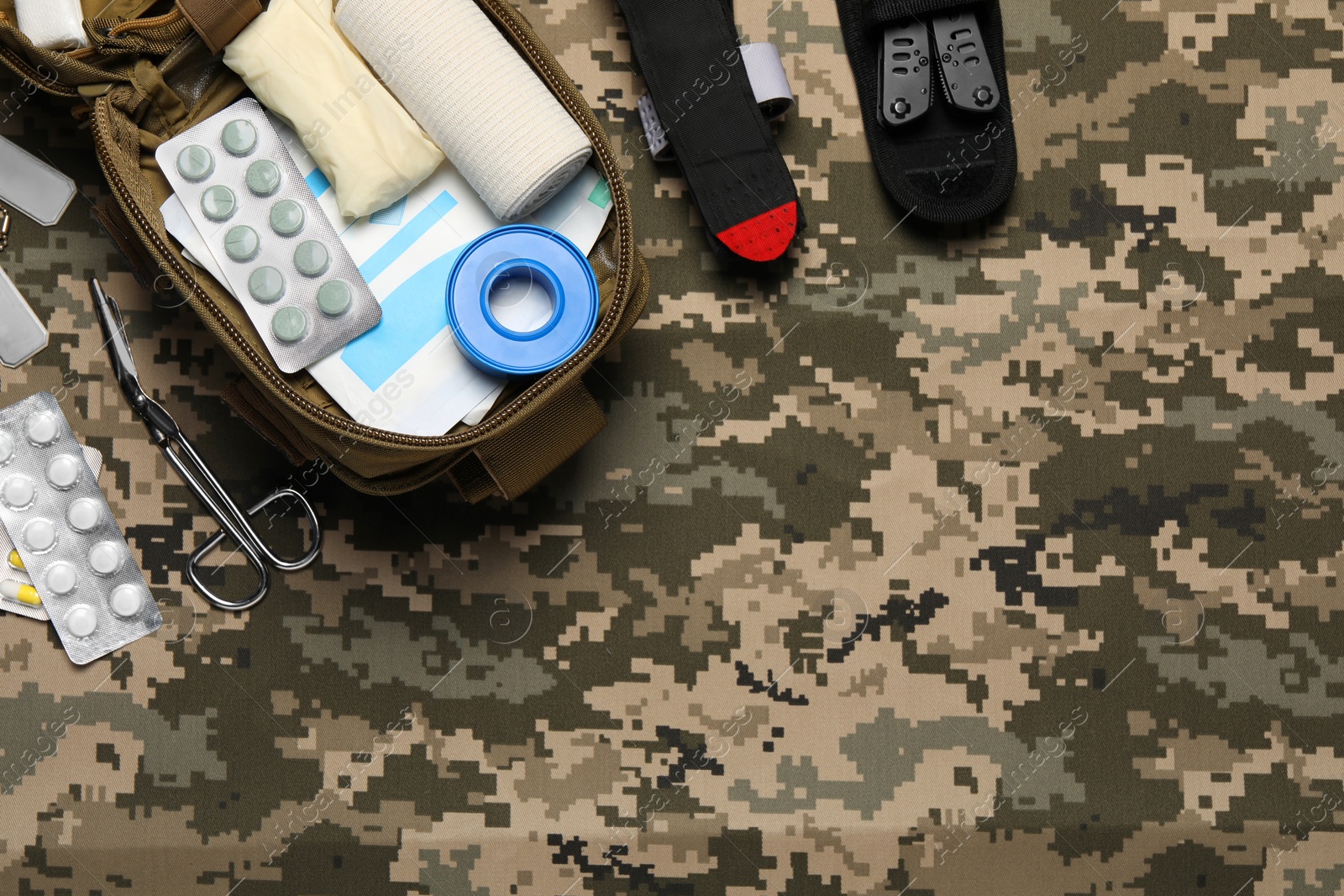 Photo of Flat lay composition with military first aid kit on camouflage fabric. Space for text