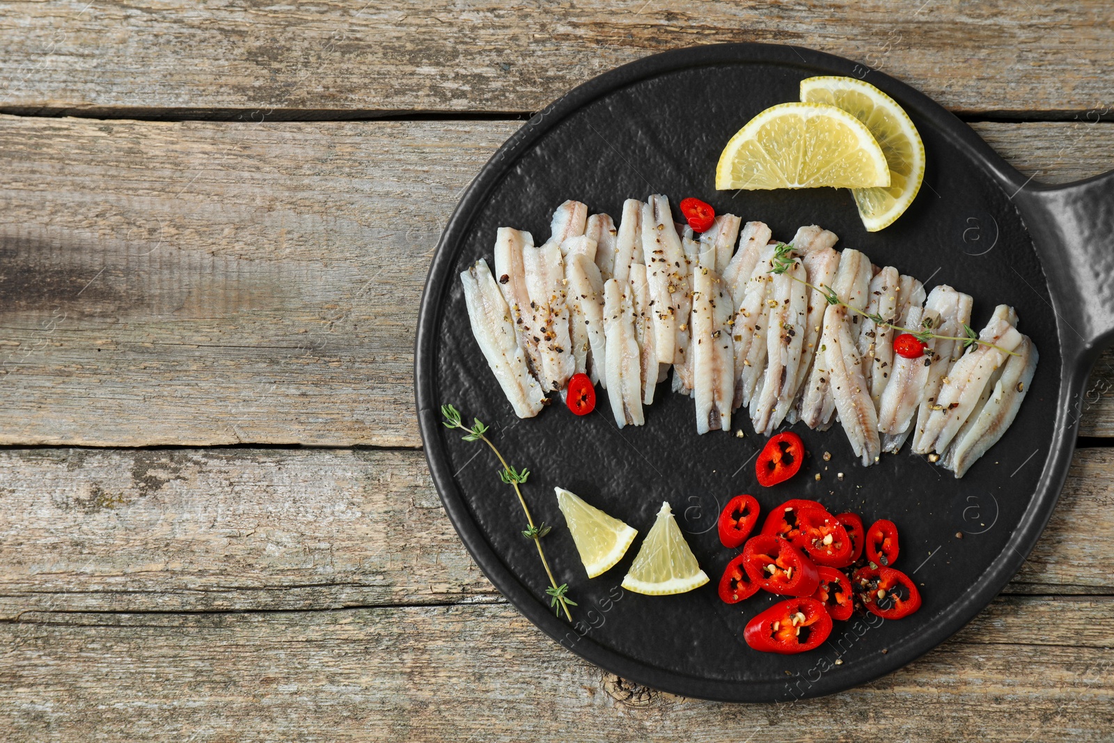 Photo of Tasty anchovies with spices and lemon slices on wooden table, top view. Space for text