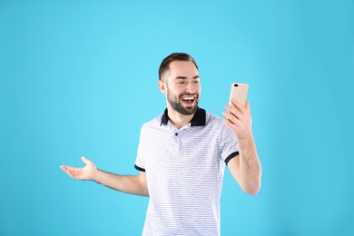 Photo of Man using mobile phone for video chat on color background