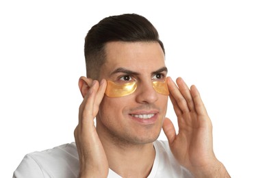 Photo of Man applying golden under eye patches on white background