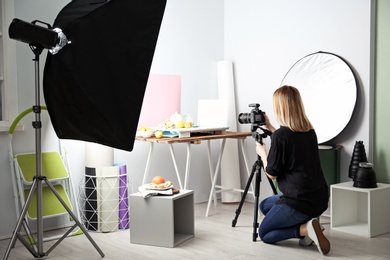 Woman taking photo of food with professional camera in studio