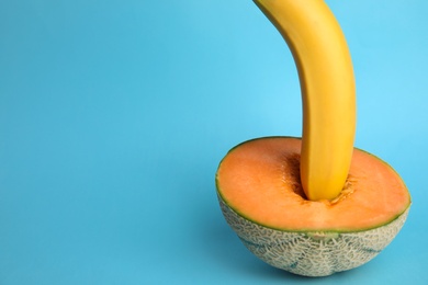 Photo of Fresh banana and melon on blue background, space for text. Sex concept