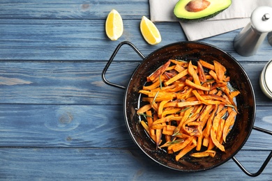 Dish with baked sweet potato slices served on wooden table, top view. Space for text