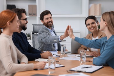 Team of employees joining hands in office