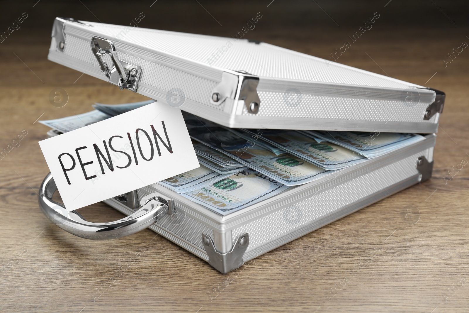 Photo of Card with word Pension and case of dollar banknotes on wooden table, closeup