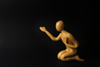 Photo of Plasticine figure of human asking help on black background. Space for text