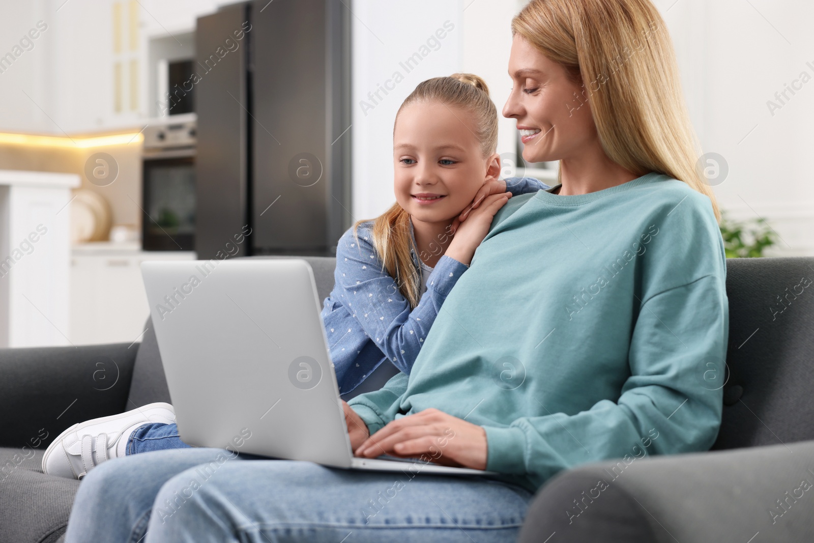 Photo of Happy woman and her daughter with laptop on sofa at home