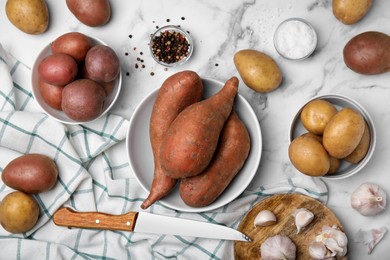 Photo of Different types of fresh potatoes on white marble table, flat lay