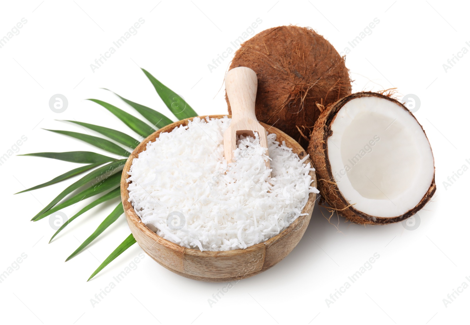 Photo of Coconut flakes in bowl, scoop, nuts and palm leaf isolated on white