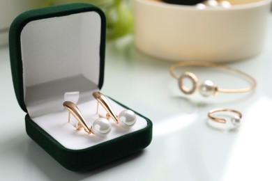 Photo of Elegant golden earrings in box on white table, closeup view