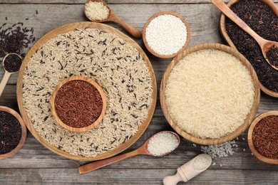 Different sorts of rice on wooden table, flat lay