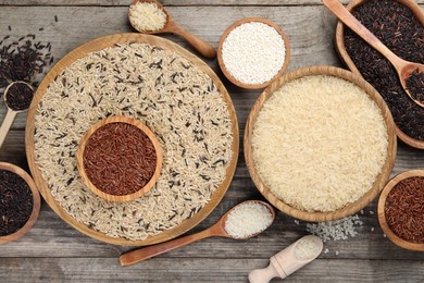 Photo of Different sorts of rice on wooden table, flat lay