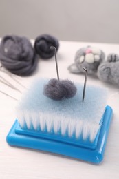 Photo of Felting tools, wool and toy cat on light wooden table, closeup