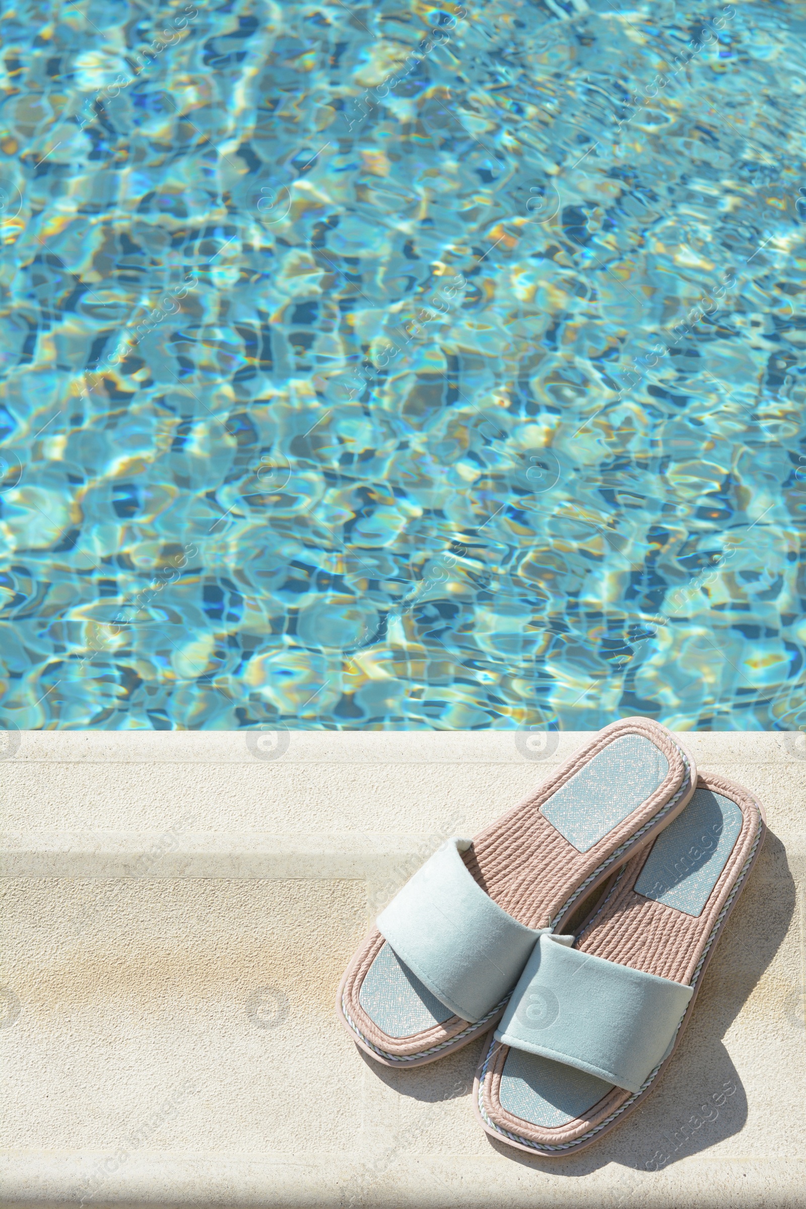 Photo of Stylish slippers near outdoor swimming pool on sunny day, space for text