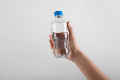 Photo of Woman holding plastic bottle with water on white background