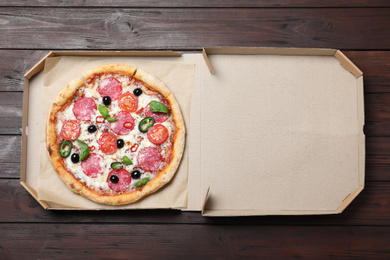 Delicious pizza Diablo in cardboard box on wooden background, top view