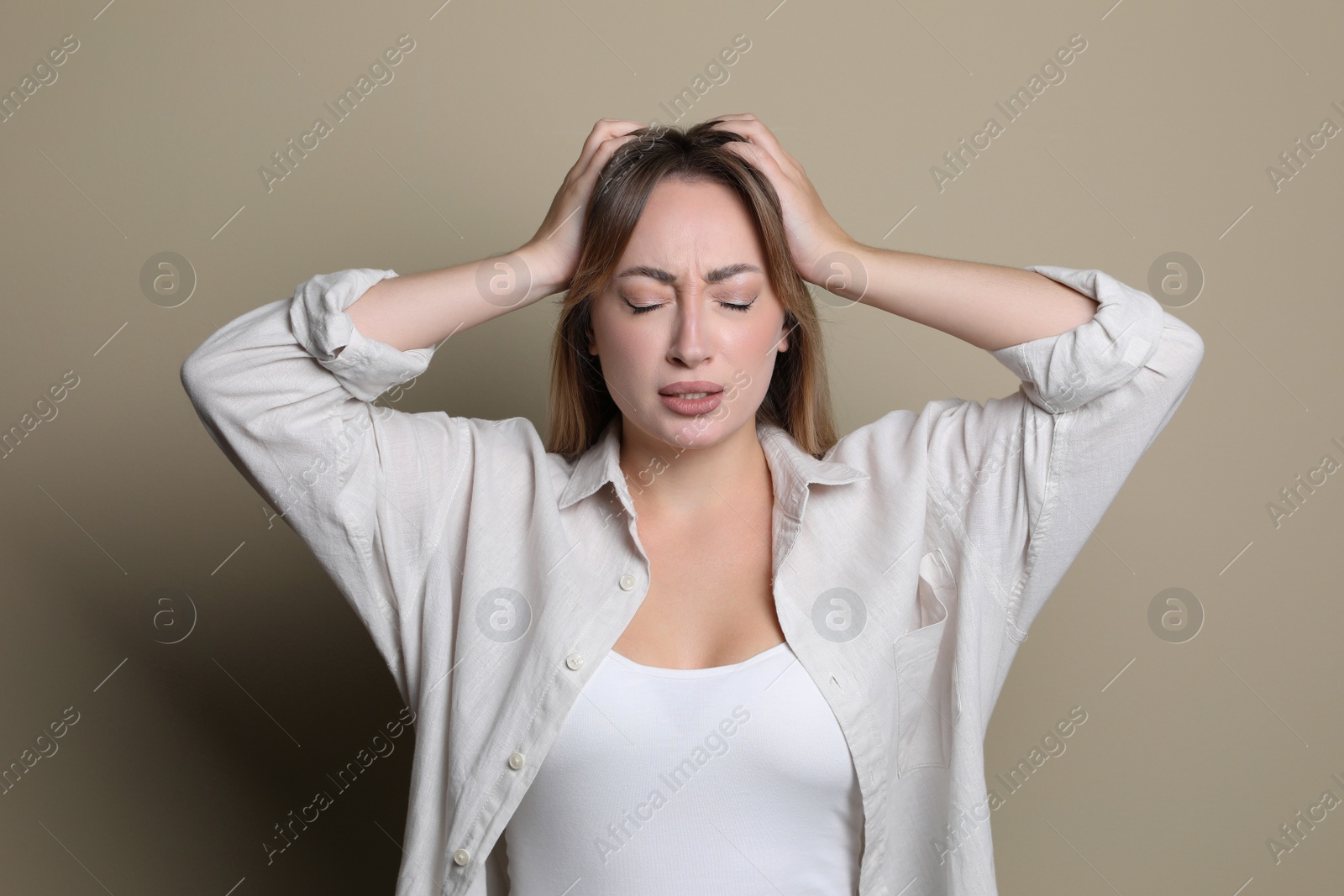 Photo of Young woman suffering from headache on beige background
