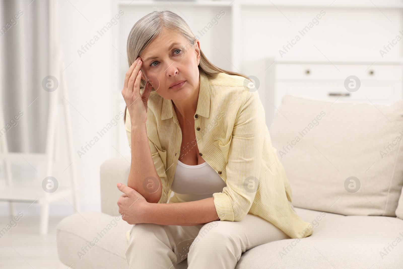 Photo of Menopause. Woman suffering from headache on sofa at home