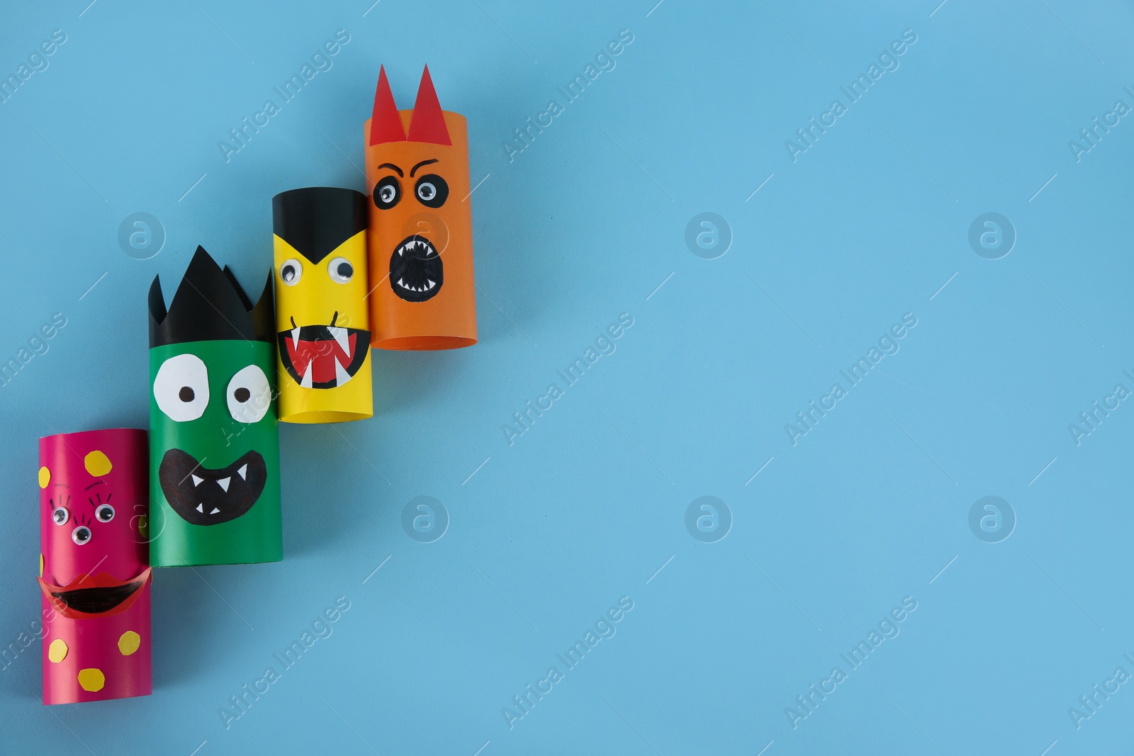 Photo of Funny monsters on light blue background, flat lay with space for text. Halloween decoration