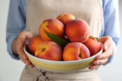 Photo of Woman with fresh sweet peaches in plate, closeup