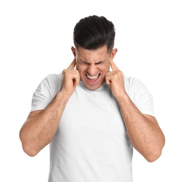 Emotional man covering ears with fingers on white background