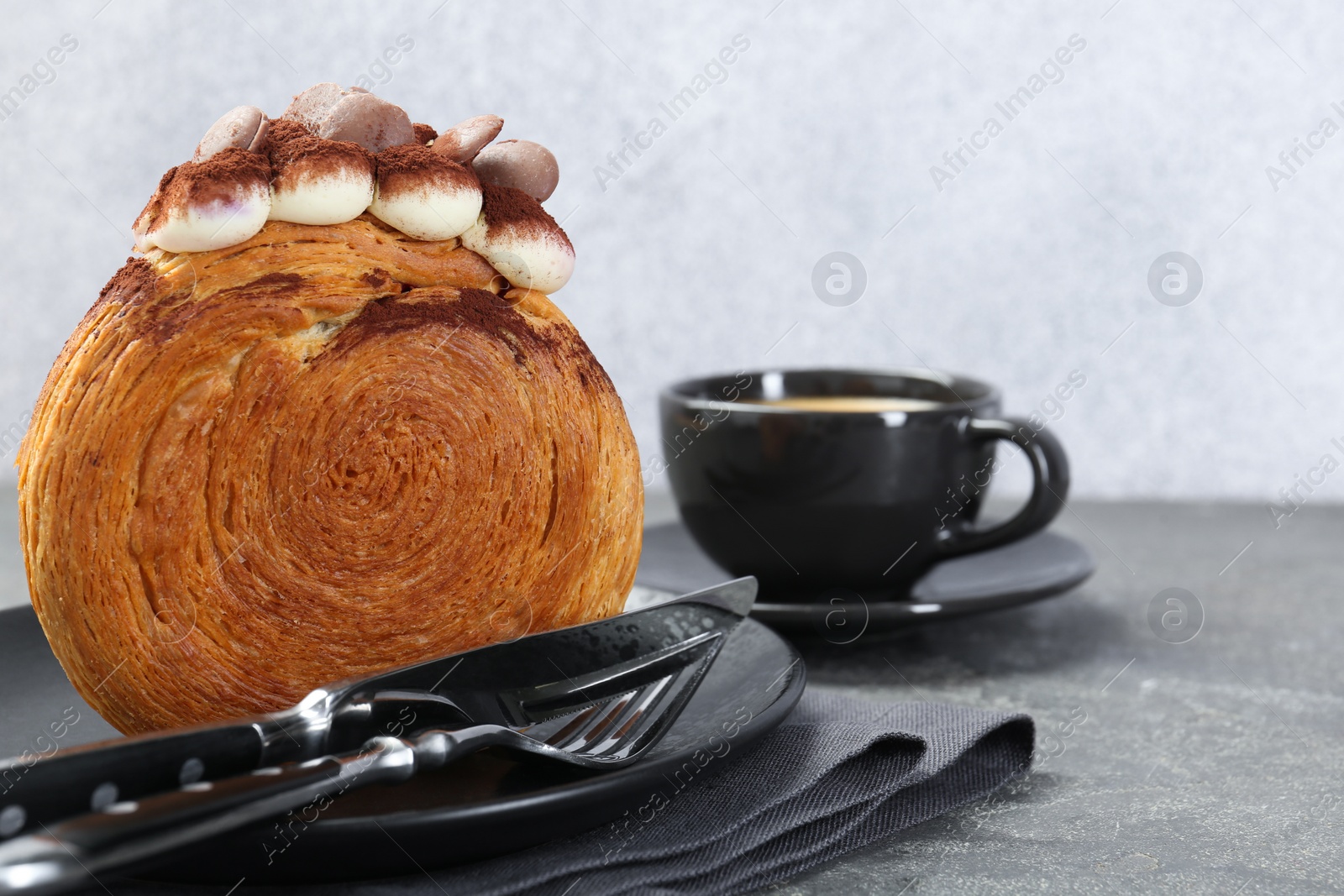Photo of Tasty puff pastry. Round croissant with chocolate chips and cream served on grey table, closeup. Space for text