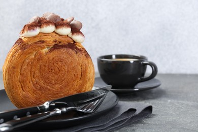 Tasty puff pastry. Round croissant with chocolate chips and cream served on grey table, closeup. Space for text