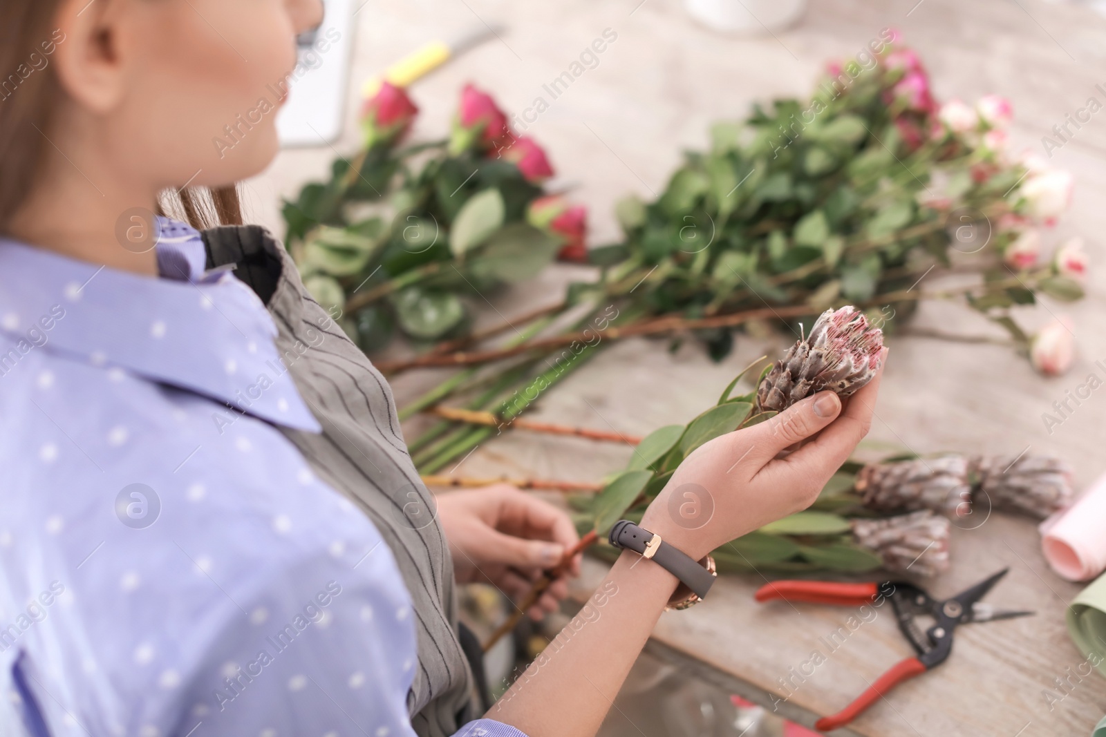 Photo of Female florist making beautiful bouquet in flower shop, closeup