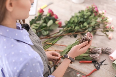 Female florist making beautiful bouquet in flower shop, closeup