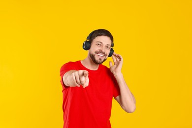 Photo of Happy man in headphones enjoying music on orange background