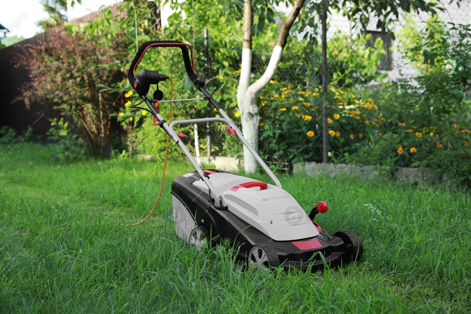 Photo of Lawn mower on green grass in garden