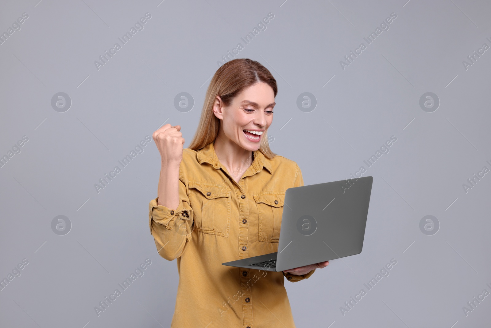 Photo of Emotional woman with laptop on light grey background