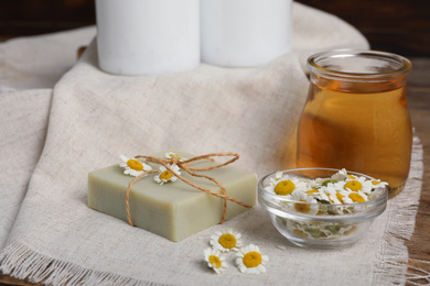 Photo of Composition with chamomile flowers and cosmetic products on wooden table