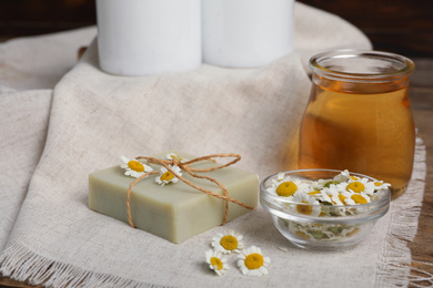 Composition with chamomile flowers and cosmetic products on wooden table