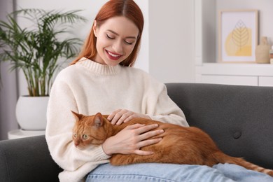 Photo of Happy woman stroking her cute cat on sofa at home