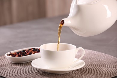 Pouring aromatic tea into cup at table, closeup