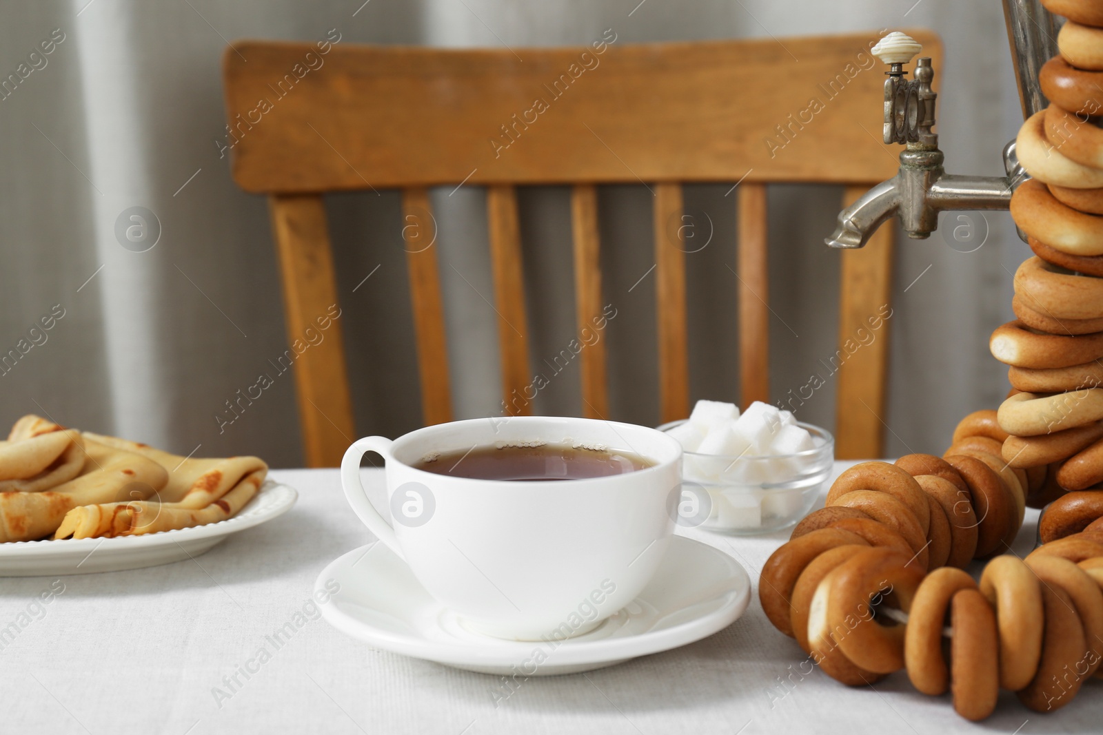 Photo of Vintage samovar, cup of hot drink and snacks served on table. Traditional Russian tea ceremony