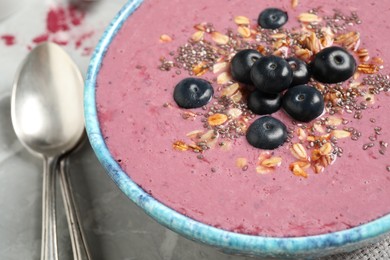 Photo of Delicious acai smoothie with granola and chia seeds served on grey  table, closeup