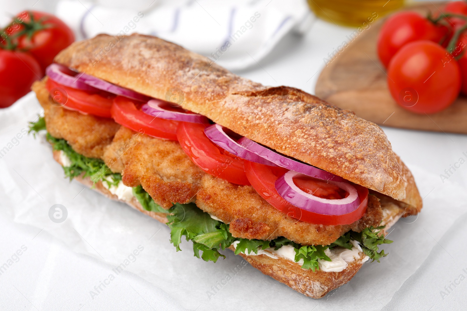 Photo of Delicious sandwich with schnitzel on white tiled table, closeup