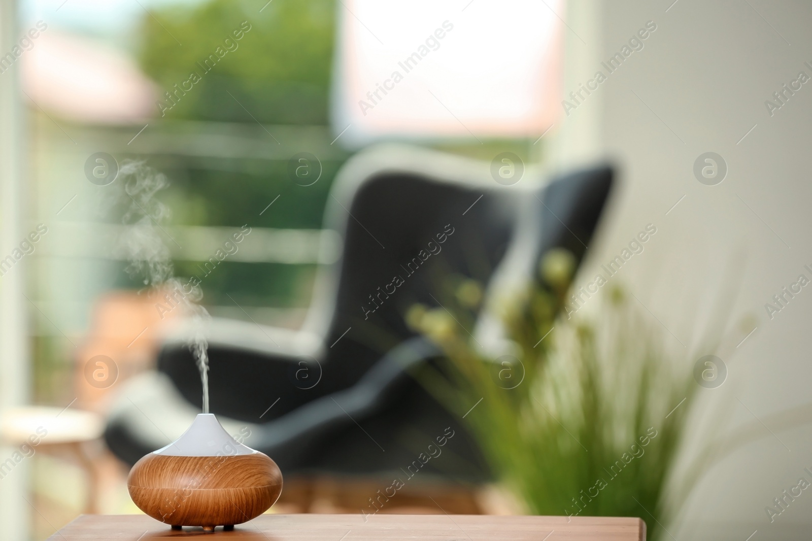 Photo of Aroma oil diffuser lamp on table against blurred background