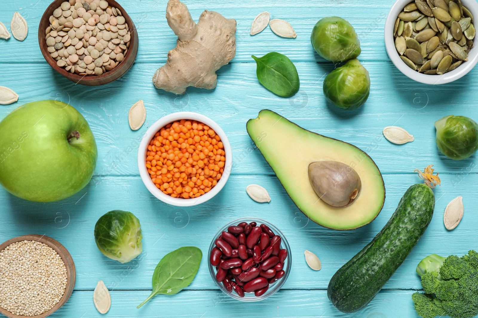 Photo of Fresh vegetables, fruits and seeds on light blue wooden table, flat lay