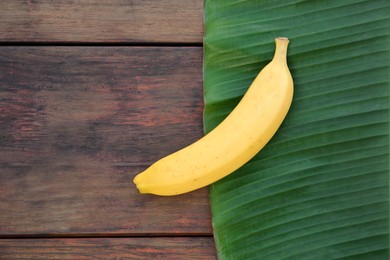 Photo of Delicious banana and green leaf on wooden table, top view. Space for text