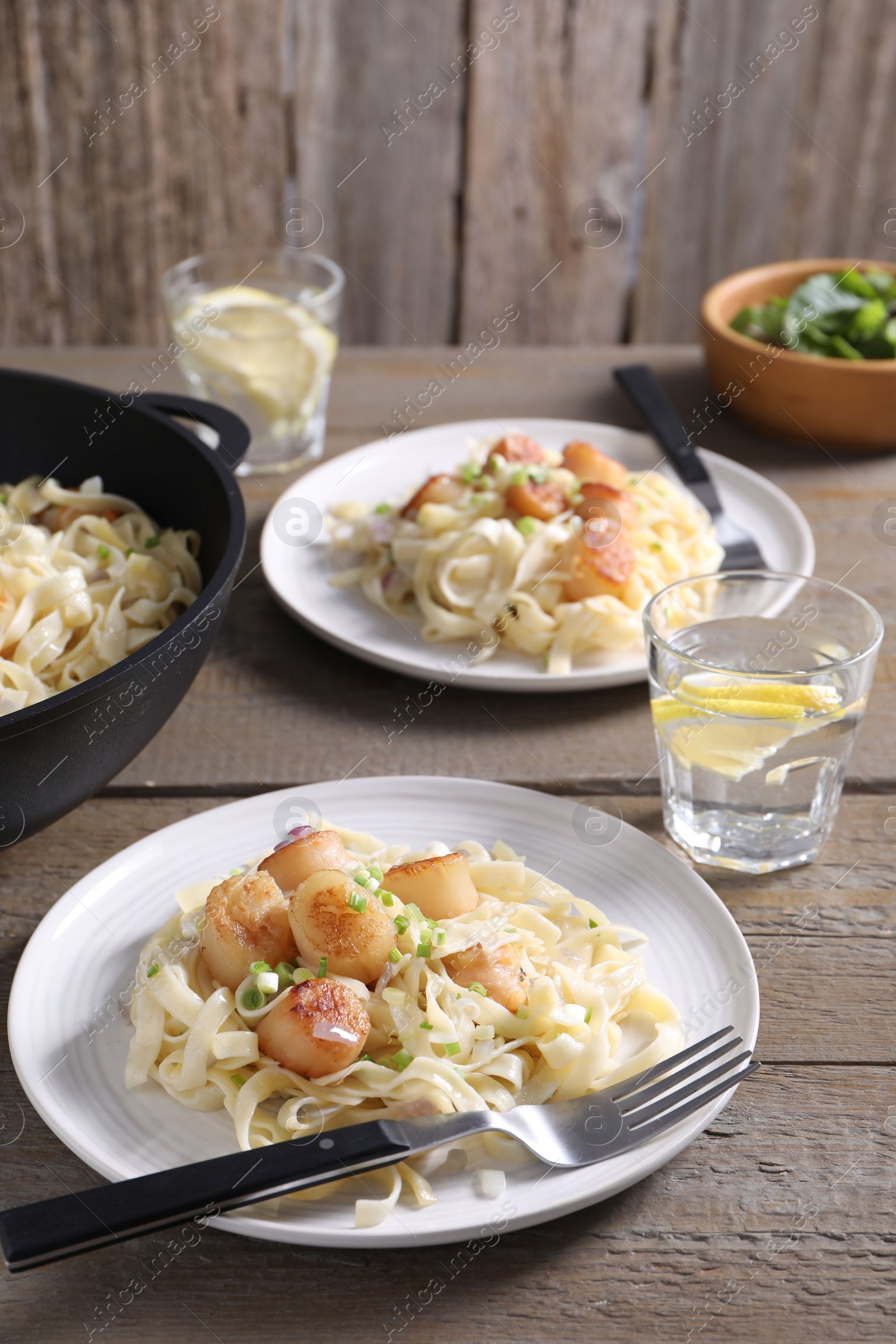 Photo of Delicious scallop pasta with onion served on wooden table