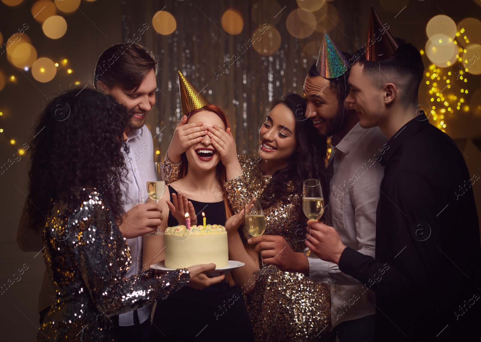 Photo of Happy friends with tasty cake and glasses of sparkling wine celebrating birthday indoors