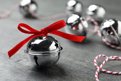 Shiny silver sleigh bell on grey stone table, closeup