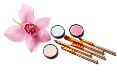 Photo of Makeup brushes with cosmetics and flower on white background