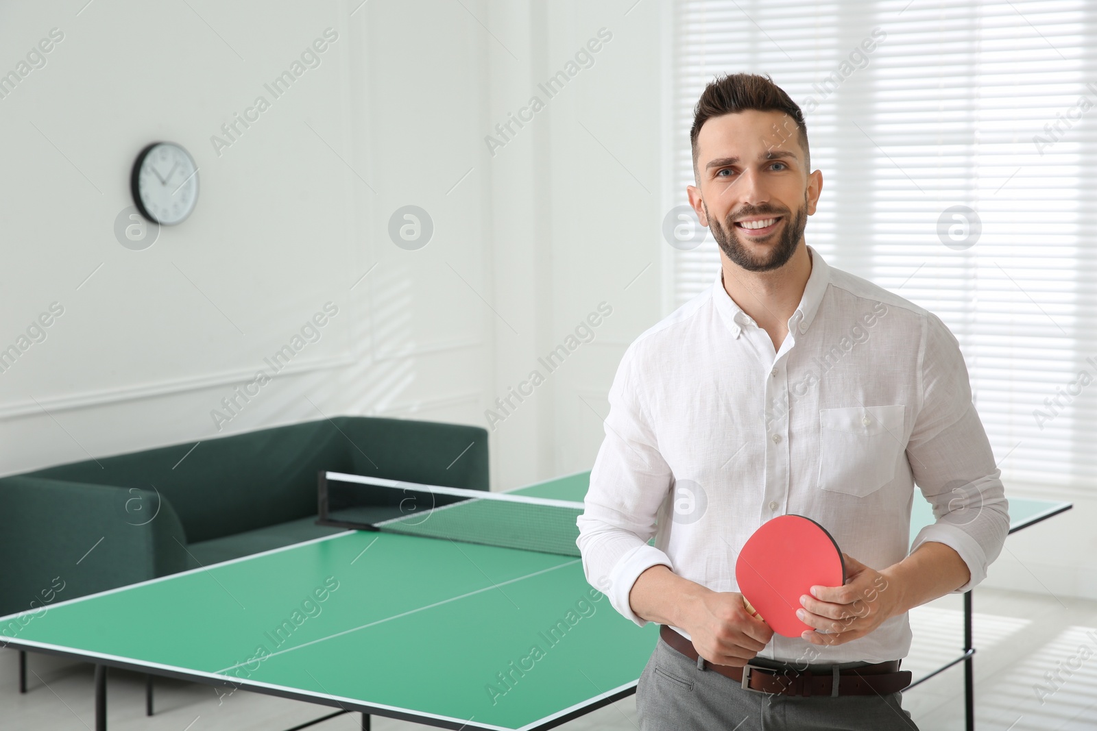 Photo of Businessman with tennis racket near ping pong table in office. Space for text