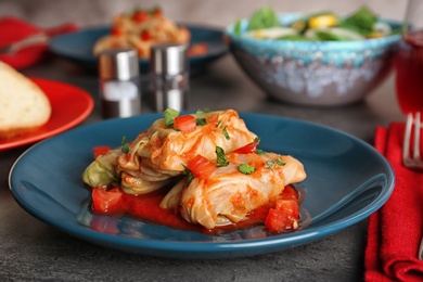 Photo of Plate with stuffed cabbage leaves in tomato sauce on table