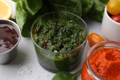 Photo of Different marinades in tableware on light table, closeup